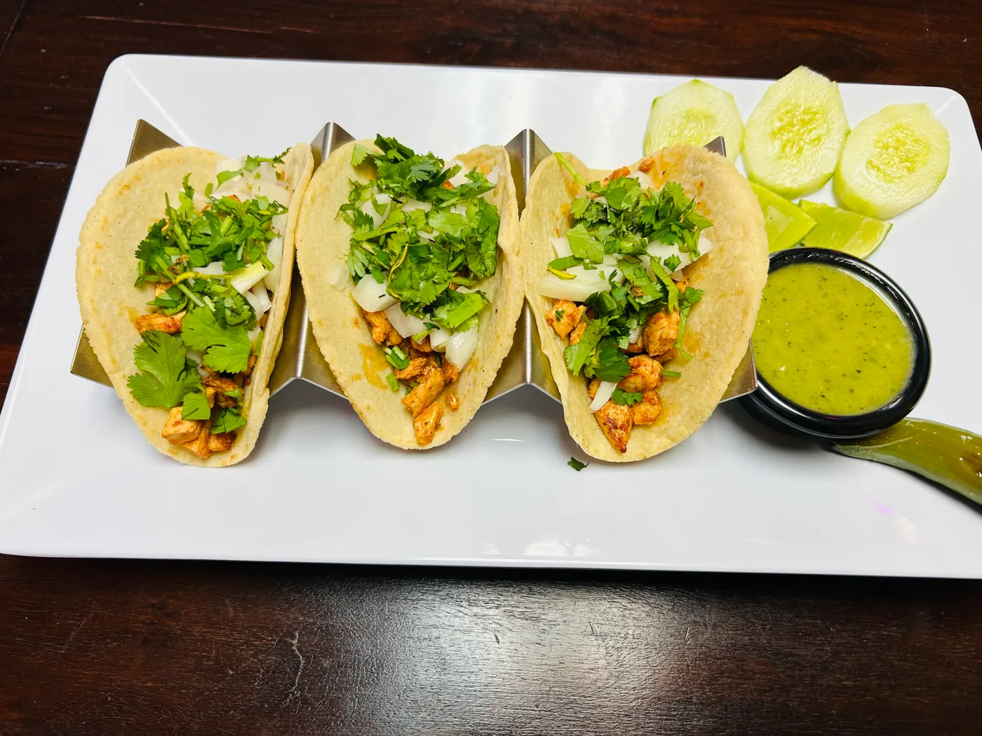Three flavorful tacos with cilantro, onions, and salsa at Jerusalen Restaurante.